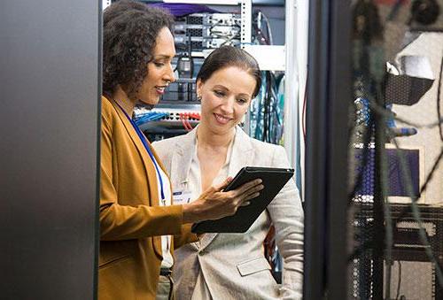 2 women viewing tablet in computer server room